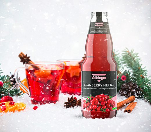 Vaihinger Cranberry-Nektar in einer winterlichen Szene mit Schnee, Tannenzweigen und zwei Tassen Punsch